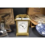 A vintage brass carriage clock having visible escape and enamel face and bevelled glass sides,