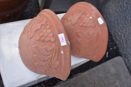 Two terracotta wall pockets