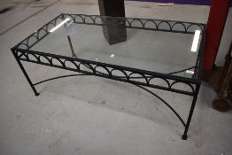 A wrought iron framed coffee table having glass top