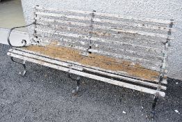 A traditional garden bench having metal frame and scroll arms, wood slat seat and back beginning