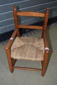 A traditional stained frame childs carver chair having rush seat