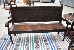 A Period oak settle having carved panel back and scroll arms, on turned front legs, width approx.