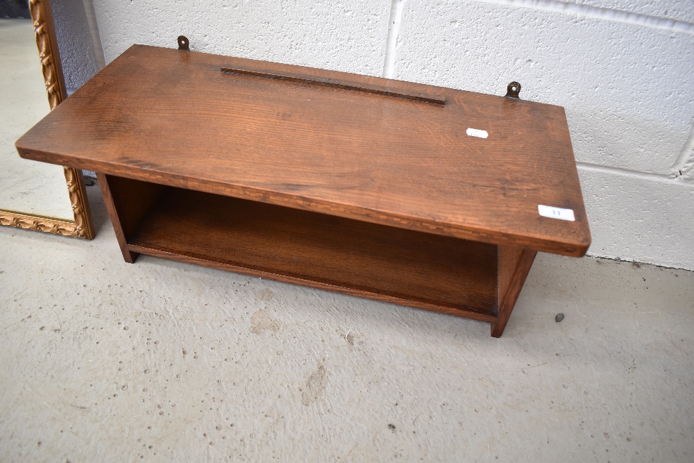 An Arts and Crafts golden oak wall shelf, labelled for Arthur Simpson Handicrafts