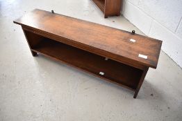 An Arts and Crafts golden oak wall shelf, labelled for Arthur Simpson Handicrafts