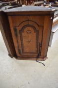 An early 19th Century oak corner cupboard with interesting inlay detail to arched panel door