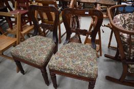 A pair of Victorian mahogany dining chairs having carved rail back and later upholstery on fluted