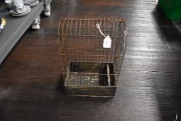 An antique bird cage having curved top and wooden base