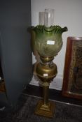 A Victorian oil lamp having gothic style well and column with pressed and etched green glass shade