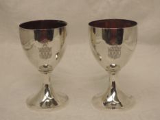 A pair of Georgian silver goblets of plain form having gilt interiors and etched crest and rampant