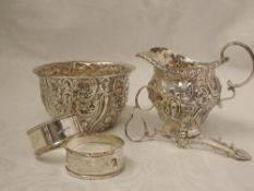 A Victorian silver cream jug and sugar bowl having extensive repousse scroll decoration and loop