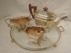 A silver three piece tea service of elongated octagonal form having paw feet and fruitwood