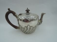 A Victorian silver bachelor teapot having moulded gadrooned decoration and fruit wood handle, London