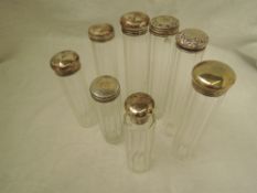 Eight cut glass cylindrical dressing table bottles having HM silver lids