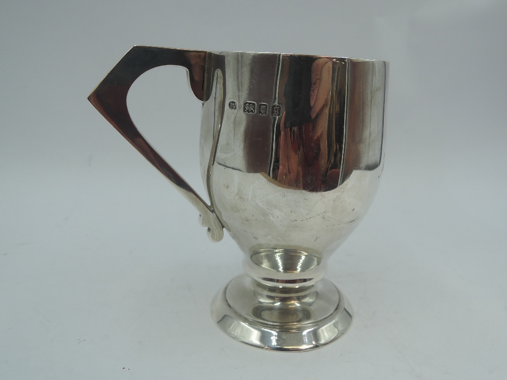 A silver Christening mug of plain stylised form bearing name to front & having angular handle,