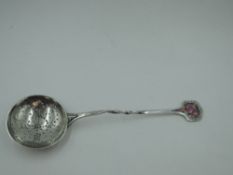 An Edwardian silver straining spoon in the Arts & Crafts style having twist stem and pink