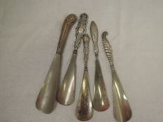 Five HM silver handled shoe horns of various forms including pistol style & shell