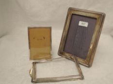 A silver photograph frame of plain rectangular form having a wooden back with easel stand and blue