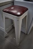 A factory style vintage stool having painted or powder coated metal frame
