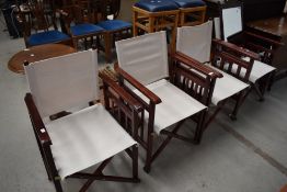 A set of four stained frame folding directors style chairs having linen seats and backs