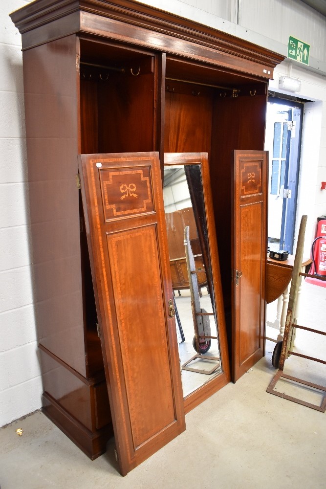 An Edwardian mahogany and inlaid mirror door triple wardrobe