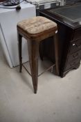 A factory style vintage stool having distressed metal frame