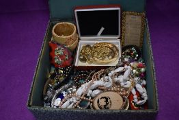 A material covered box containing a selection of costume jewellery including gold plated items,