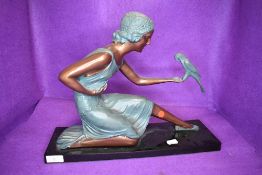 A reproduction art deco figure of a lady holding a parrot