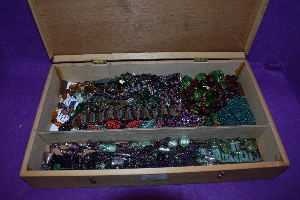A wooden box containing a selection of beaded necklaces, bracelets and book marks