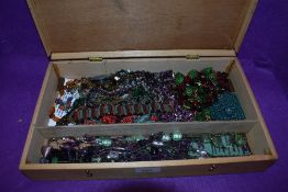 A wooden box containing a selection of beaded necklaces, bracelets and book marks