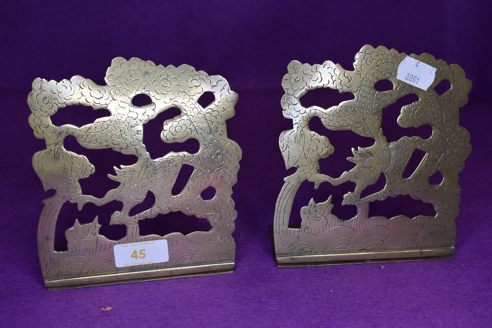 a pair of fold out brass book ends chased with Chinese dragon image