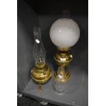 Two brass bodied oil burning lamps and a milk glass shade