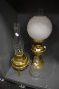 Two brass bodied oil burning lamps and a milk glass shade