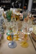 An assortment of coloured glasses including etched wine glasses.
