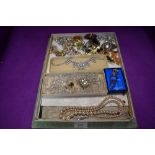 A vintage chocolate box containing a selection of costume brooches and necklaces including crystal