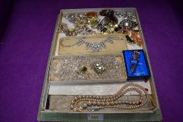 A vintage chocolate box containing a selection of costume brooches and necklaces including crystal