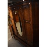 An early 20th Century oak mirror door wardrobe having drawer base