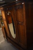 An early 20th Century oak mirror door wardrobe having drawer base