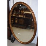 A late 19th or early 20th Century large giltwood/gesso wall mirror of oval form, having lozenge bead