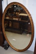 A late 19th or early 20th Century large giltwood/gesso wall mirror of oval form, having lozenge bead