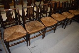 A set of six rail back dining/kitchen chairs having rush seats and a further rocking chair of