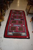 A traditional wool rug in shades of burgundy brown and sky blue , approx. 150 x 72cm