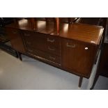A vintage teak effect sideboard having central drawer section flanked by cupboard having stylised