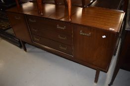 A vintage teak effect sideboard having central drawer section flanked by cupboard having stylised