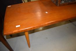 A 1970s teak coffee table on tapered legs, approx. 135 x 55cm