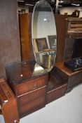 A mid century dark wood veneered dressing table having oval mirror and four drawers