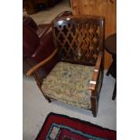 An early 20th Century stained frame and open ply back low seat armchair