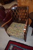 An early 20th Century stained frame and open ply back low seat armchair