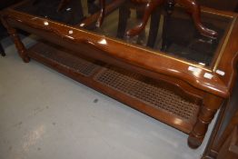 A modern glass top coffee table in the classical style having canework undertier, approx 132 x 57cm