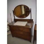 An early 20th Century oak dressing table having oval mirror back and two over two drawer base,