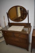 An early 20th Century oak dressing table having oval mirror back and two over two drawer base,